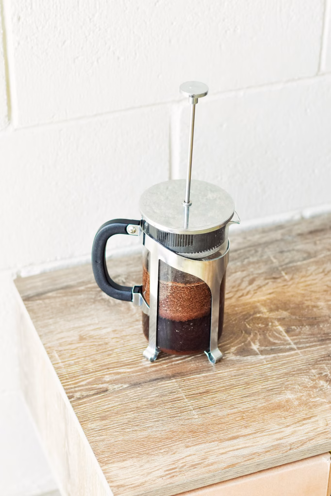Cafetière à piston remplie de café sur une table en bois